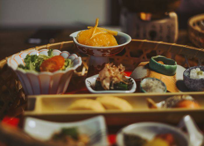 A table laid out with a wide array of Japanese traditional food including sashimi, salad and small appetizers.